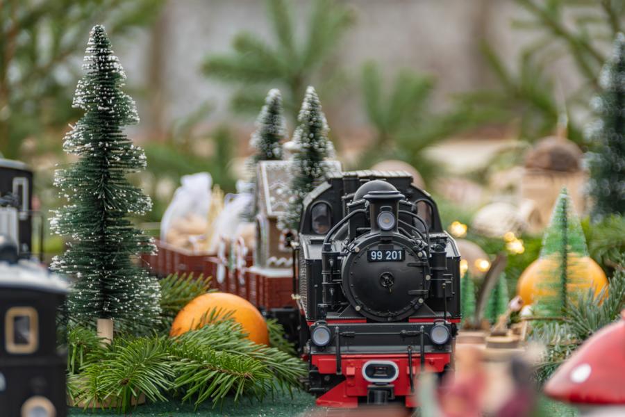 Nahaufnahme  Modell-Lok in Winterlandschaft auf weihnachtlich dekorierter Modellbahnplatte.