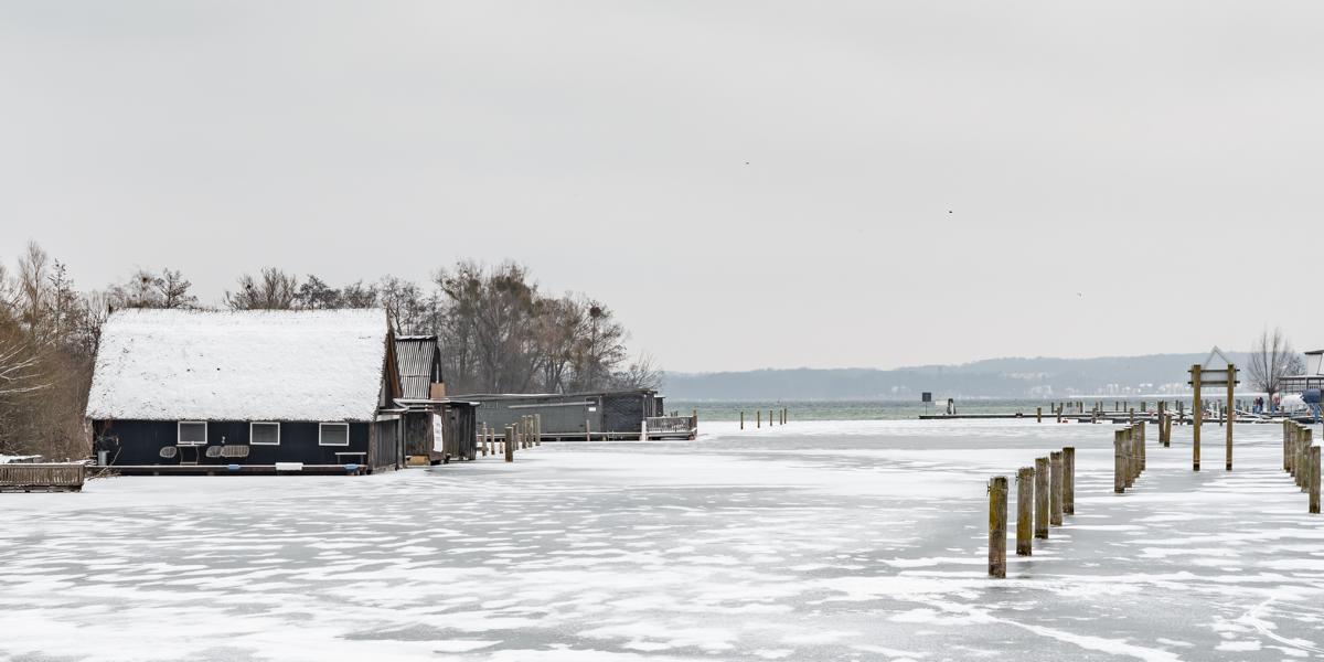 Bootshaus am Schweriner Hafen mit zugefrorenen See im Winter